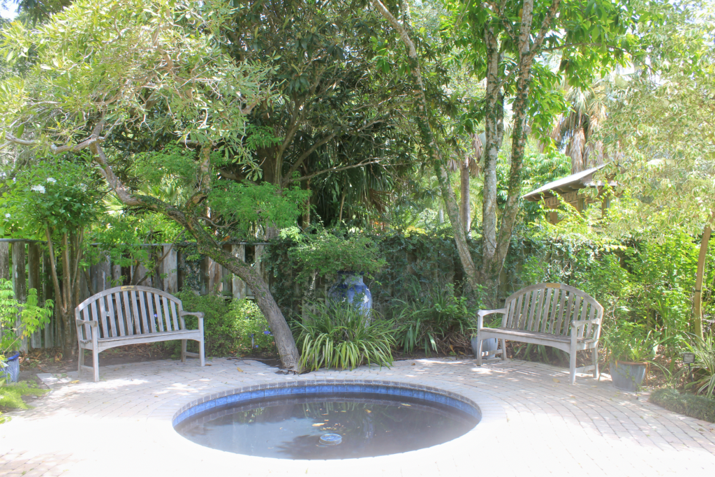 Refelction pond with the two benches behind it in the shade