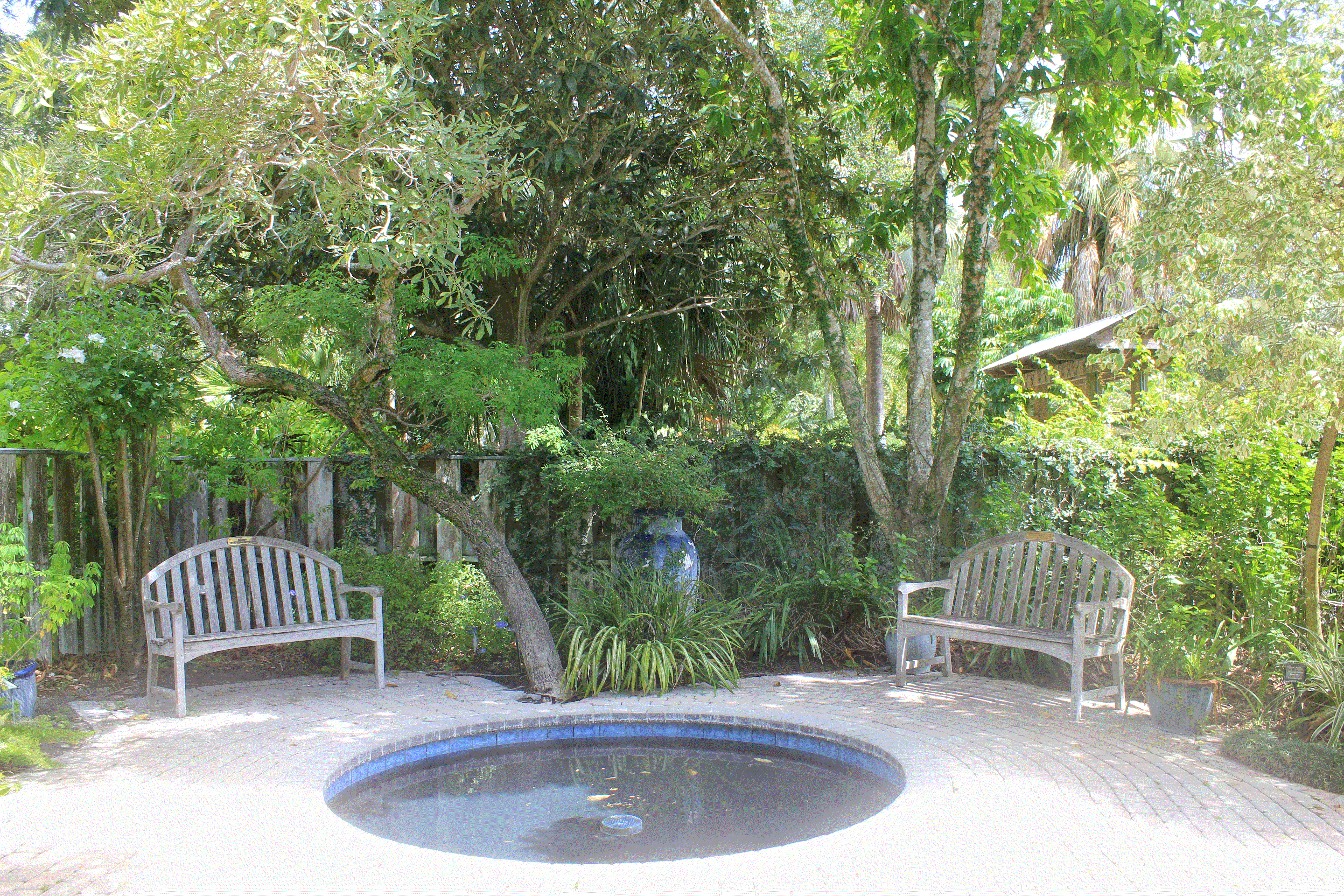 Refelction pond with the two benches behind it in the shade